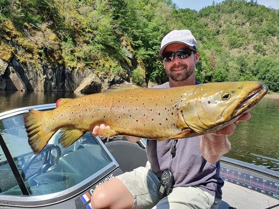 Pêcheur présentant un brochet pris en bateau sur un lac de barrage du Limousin