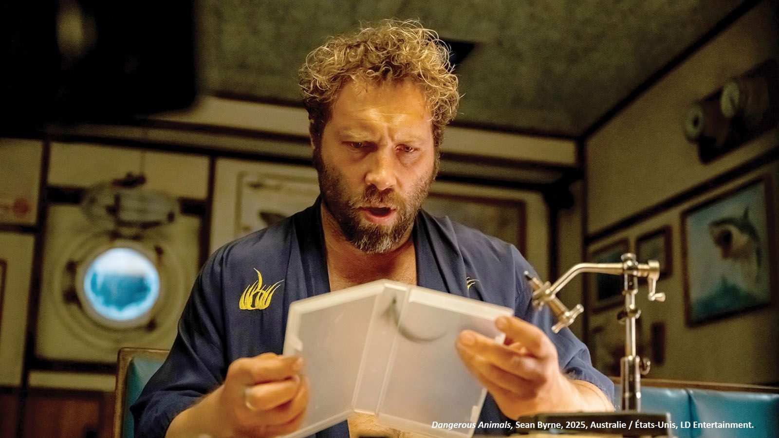 Le tueur Tucker examinant une boîte à mouches devant son étau de montage, dans le film Dangerous Animals
