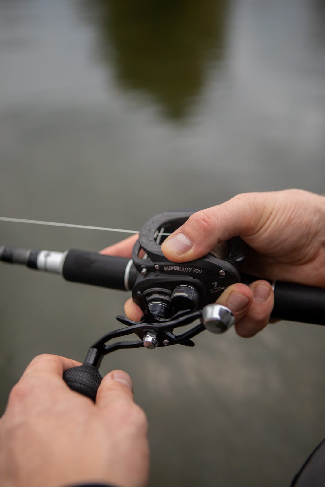 Mains d’un pêcheur sur un moulinet casting, prêtes à ferrer un brochet