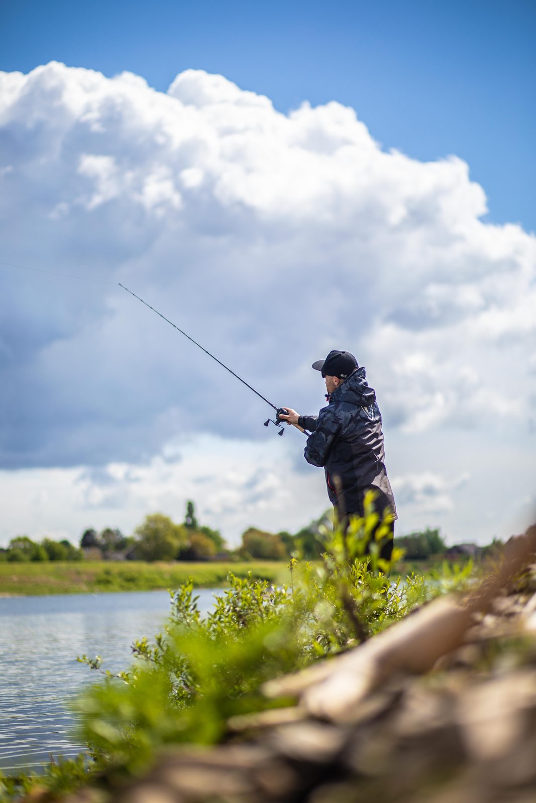 Pêcheur lançant un leurre depuis la berge d’une gravière pour pêcher le gros brochet