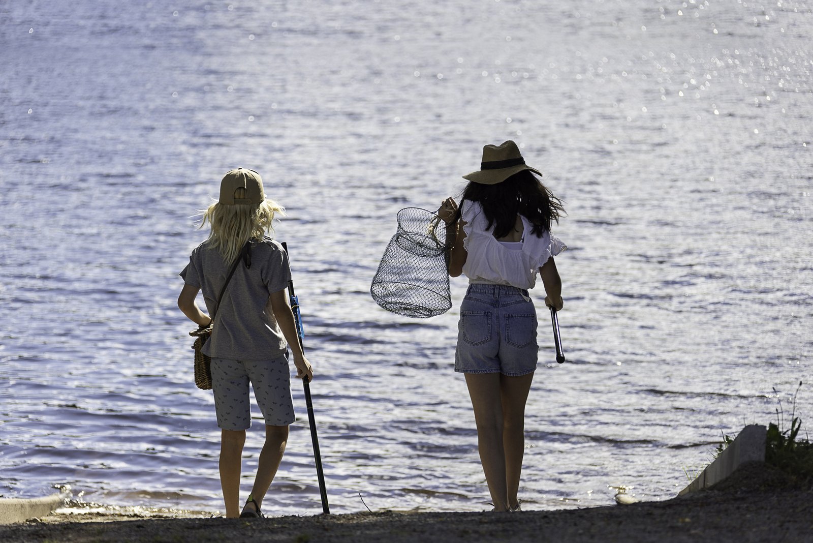 Deux pêcheurs marchant au bord d'un lac avec une épuisette, image de la transmission de la passion de la pêche